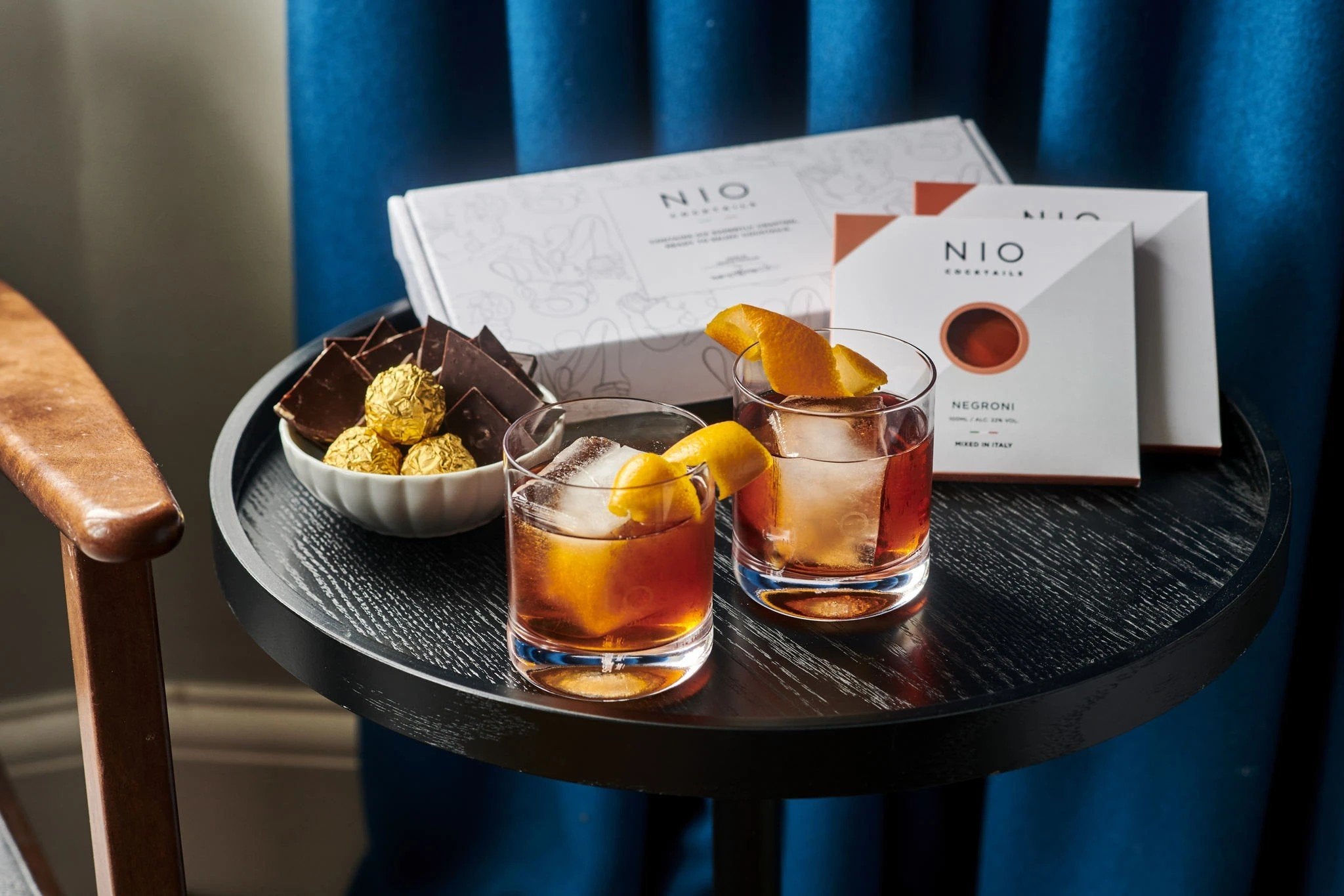 NIO Cocktails UK white box with bitter and sweet cocktails on living room table with orange peal and dark chocolate